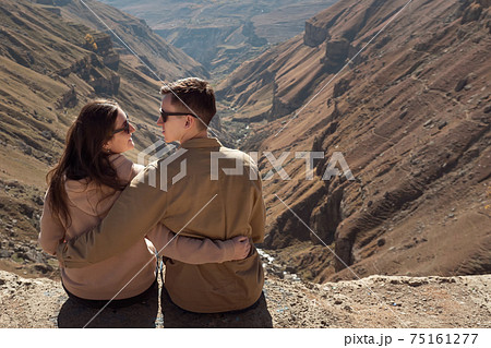 Romantic couple in love hugs sitting on mountain cliff edge 75161277