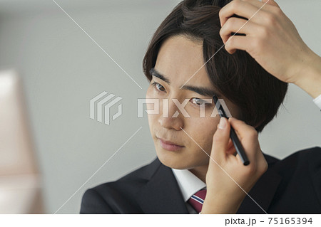 眉を描くスーツ姿の若い男性 メンズメイク イメージの写真素材