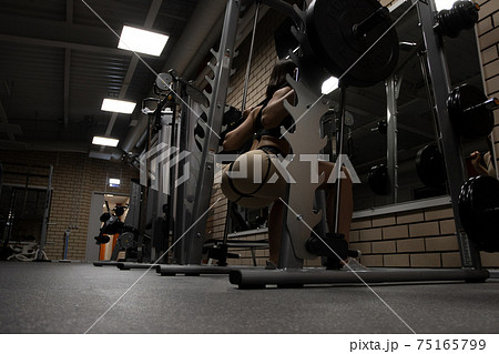 Fit woman squatting with barbell in gym 75165799
