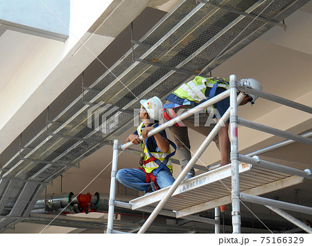 KAJANG, MALAYSIA -JUNE 16, 2017: Construction workers installing hanging type electrical metal cable tray.  75166329