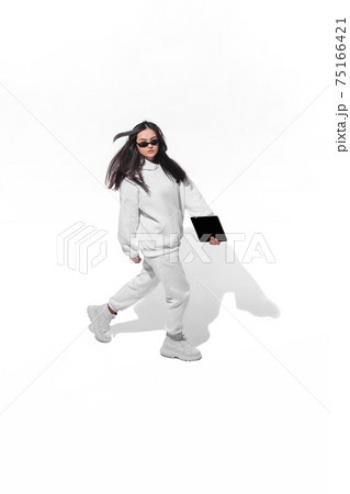High angle view of young woman on white studio background. Girl in motion or movement. Human emotions and facial expressions concept High angle view of young woman on white studio background. Girl in motion or movement. Human emotions and facial expressions concept 75166421