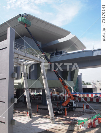 JOHOR, MALAYSIA -MAY 16, 2017: Construction workers standing in the mobile crane bucket while working at high level in the construction site. The bucket movement control by the workers himself. JOHOR, MALAYSIA -MAY 16, 2017: Construction workers standing in the mobile crane bucket while working at high level in the construction site. The bucket movement control by the workers himself. 75170141