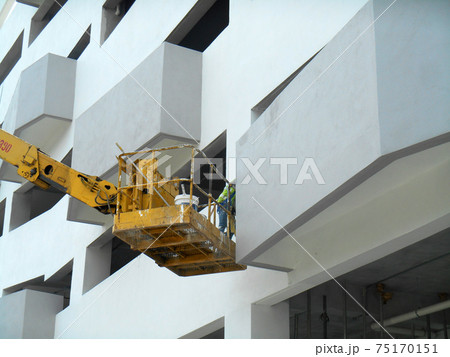 JOHOR, MALAYSIA -MAY 16, 2017: Construction workers standing in the mobile crane bucket while working at high level in the construction site. The bucket movement control by the workers himself. JOHOR, MALAYSIA -MAY 16, 2017: Construction workers standing in the mobile crane bucket while working at high level in the construction site. The bucket movement control by the workers himself. 75170151