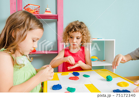 The kids sit at the desk and molding clay 75172340