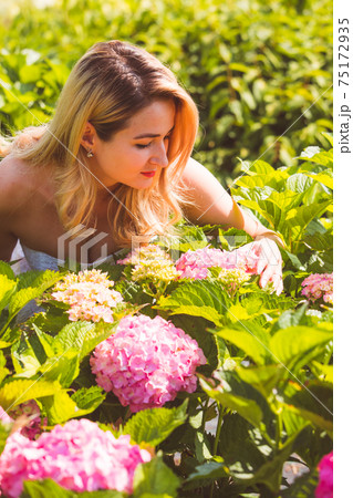 Woman posing outdoors at flowers market between hydrangea flowers Woman posing outdoors at flowers market between hydrangea flowers 75172935
