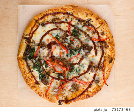 Pizza on a wooden table close-up. Freshly baked pizza on a wooden surface. Top View. Pizza on a wooden table close-up. Freshly baked pizza on a wooden surface. Top View. 75173468