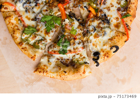 Pizza on a wooden table close-up. Freshly baked pizza on a wooden surface close-up. Top View. 75173469