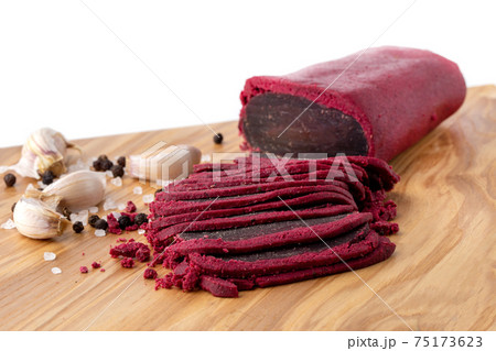 Cured meat on a wooden board. Close-up of basturma sliced into pieces. 75173623