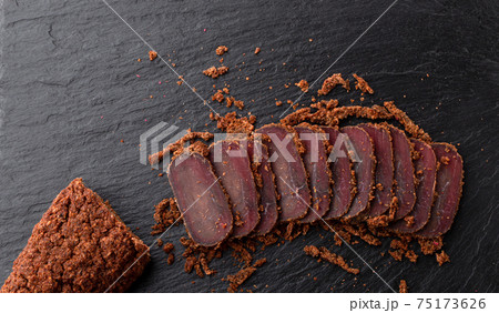 Cured meat on a slate board. Close-up of basturma sliced into pieces. Cured meat on a slate board. Close-up of basturma sliced into pieces. 75173626