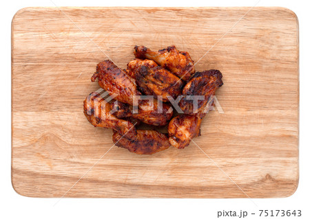 Fried wings close-up. Buffalo wings on a wooden board isolated on a white background. Top view. Fried wings close-up. Buffalo wings on a wooden board isolated on a white background. Top view. 75173643