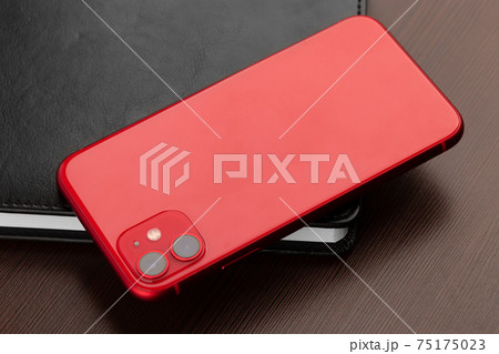 Smartphone with red color on a wooden table close-up. 75175023