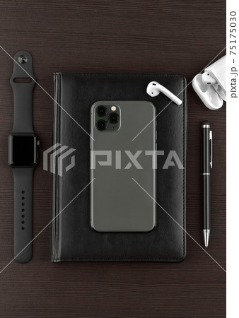 A smartphone with three cameras, a smart watch and wireless headphones on a wooden table. A smartphone with three cameras, a smart watch and wireless headphones on a wooden table. 75175030