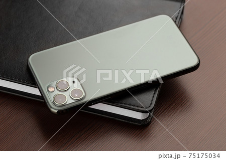 Smartphone with three cameras on a wooden table close-up. Smartphone with three cameras on a wooden table close-up. 75175034