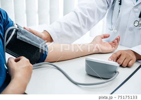 Doctor is checking the patient blood pressure in his hospital office Doctor is checking the patient blood pressure in his hospital office 75175133