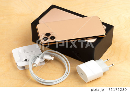 Smartphone on a wooden surface. A popular smartphone and a kit from it and a box close-up. 75175280