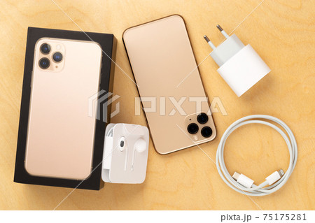 Smartphone on a wooden surface. A popular smartphone and a kit from it and a box close-up. 75175281