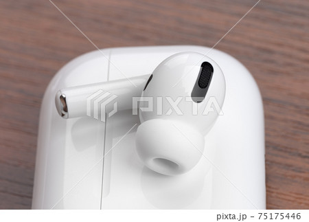 Wireless headphones on a wooden table. Wireless headset and charging case close-up. Wireless headphones on a wooden table. Wireless headset and charging case close-up. 75175446