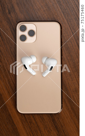 Smartphone on a wooden surface. A popular smartphone and wireless headset close-up. Smartphone on a wooden surface. A popular smartphone and wireless headset close-up. 75175460