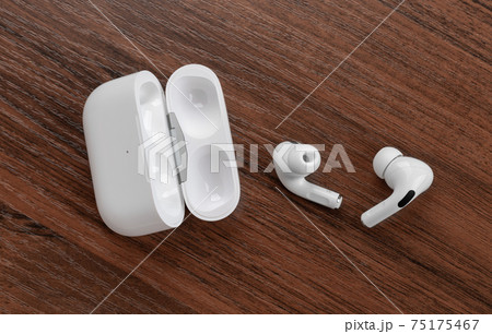 Wireless headphones on a wooden table. Wireless headset and charging case close-up. 75175467