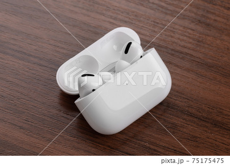 Wireless headphones on a wooden table. Wireless headset and charging case close-up. 75175475