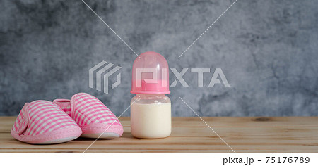 Objects on the table of decoration Happy Mother's day holiday background concept. Bottle milk and pink baby shoes. Blur grey color backdrop. Design copy space banner. Mock up infant child of kids. Objects on the table of decoration Happy Mother's day holiday background concept. Bottle milk and pink baby shoes. Blur grey color backdrop. Design copy space banner. Mock up infant child of kids. 75176789