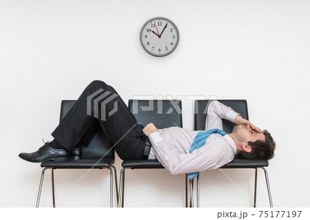 Tired bored man is sleeping in waiting room on chairs. 75177197