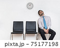 Tired and exhausted man is sitting in waiting room on chair. 75177198