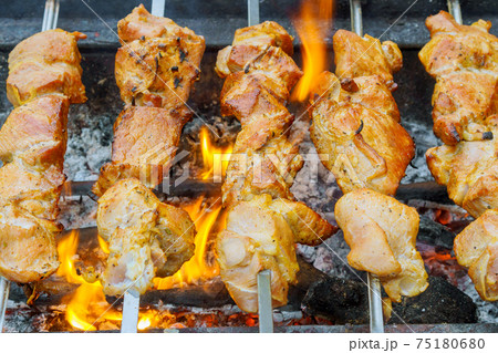 closeup of some meat skewers being grilled in a barbecue closeup of some meat skewers being grilled in a barbecue 75180680