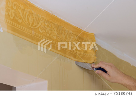 Preparing for home repair work man hand tear off old light wallpaper from wall 75180743