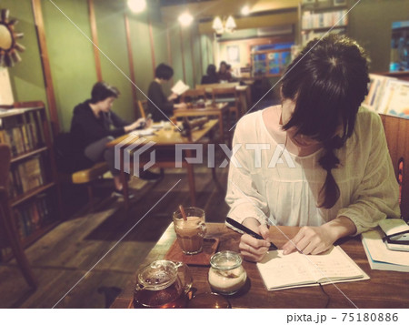 カフェにて　ノートに文字を書く勉強中の三つ編みの女性 75180886
