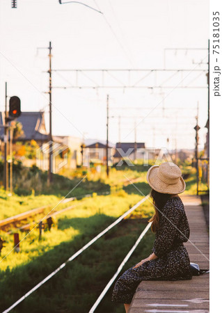 田舎の駅のプラットフォームに座る麦わら帽子をかぶったロングヘアの女性 田舎の駅のプラットフォームに座る麦わら帽子をかぶったロングヘアの女性 75181035