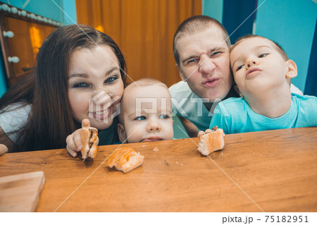 the family eats cakes. dinner at the bakery. feast in the kitchen. the butchering of the food. a woman cuts a pie with a knife the family eats cakes. dinner at the bakery. feast in the kitchen. the butchering of the food. a woman cuts a pie with a knife 75182951