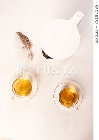 Two mugs of herbal tea and teapot on white. Top view. Concept of good morning, easy start to day Two mugs of herbal tea and teapot on white. Top view. Concept of good morning, easy start to day 75185195