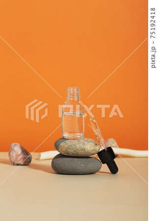 Bottle white glass with dropper on orange background. Natural cosmetic product for skincare concept. Natural materials, rock balancing 75192418