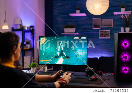 Concentrated player sitting on gaming desk late at night 75192532