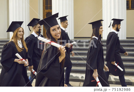 Group of young happy university graduates mates walking with diplomas 75192986