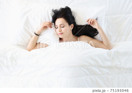 Young brunette woman sleeping in white bed top view Young brunette woman sleeping in white bed top view 75193046