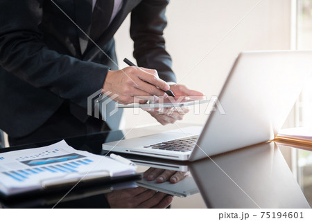 Businessman working at home with tablet and laptop computer and papers on desk. 75194601