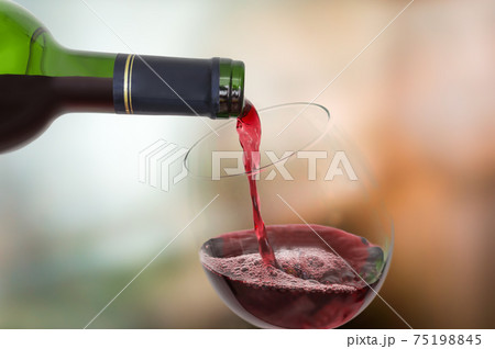 Red wine pouring into a wine glass - celebration concept Red wine pouring into a wine glass - celebration concept 75198845
