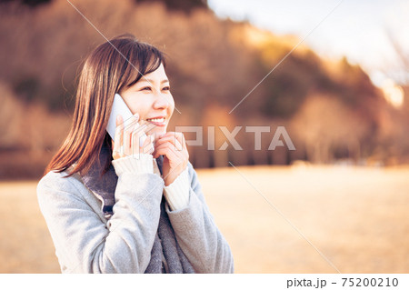 紅葉の公園で電話をする女性 75200210