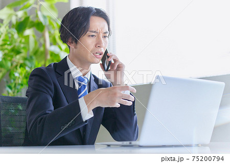 怒りながらスマホで通話するビジネスマン 75200794