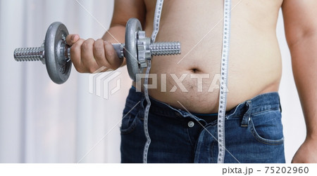 Overweight man exercising by lifting weight with a dumbbell. 75202960