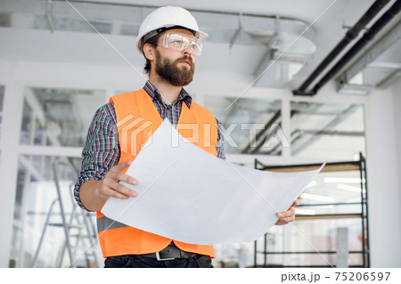 Young handsome arhitect posing indoors with building drawings 75206597