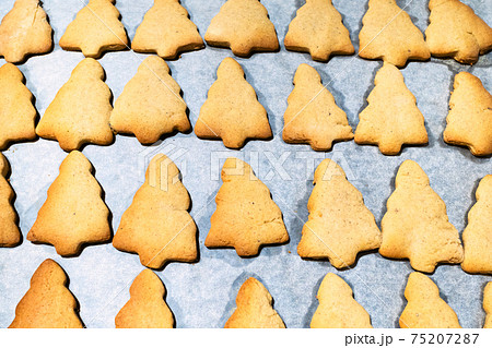 Christmas tree-shaped cookies on parchment paper Christmas tree-shaped cookies on parchment paper 75207287