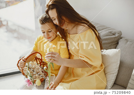 Mother and son inspect Easter eggs and put them in a basket 75209840