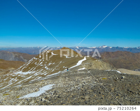 A lonely hiker approaching Piz d'Immez, Switzerland, through a rocky desert A lonely hiker approaching Piz d'Immez, Switzerland, through a rocky desert 75210264