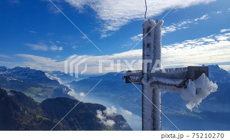 Icy summit cross on the top of Federispitz, a Swiss mountain. View to Walensee. Icy summit cross on the top of Federispitz, a Swiss mountain. View to Walensee. 75210270