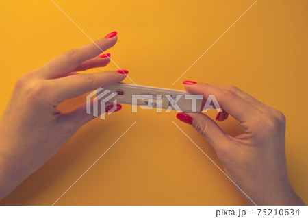 test for coronavirus on an orange background. medical analysis. girl with bright red manicure holding a test for antibodies to coronavirus test for coronavirus on an orange background. medical analysis. girl with bright red manicure holding a test for antibodies to coronavirus 75210634