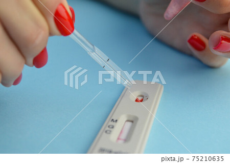 test for coronavirus on a blue background. girl with a bright red manicure makes a blood test. a drop of blood on the sensitive test strip 75210635