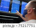 Young man protect his health with a medical mask an airport time table terminal background 75217751